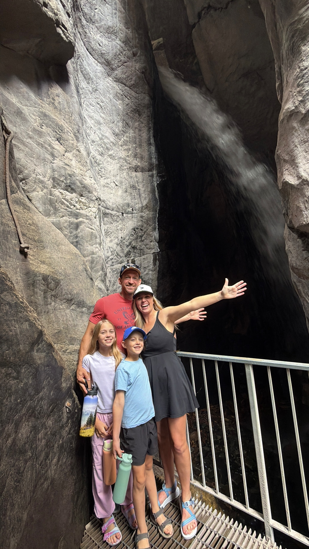Our family standing on the walkway inside the gorge at Box Canyon Falls in Ouray, Colorado with the waterfall rushing behind us