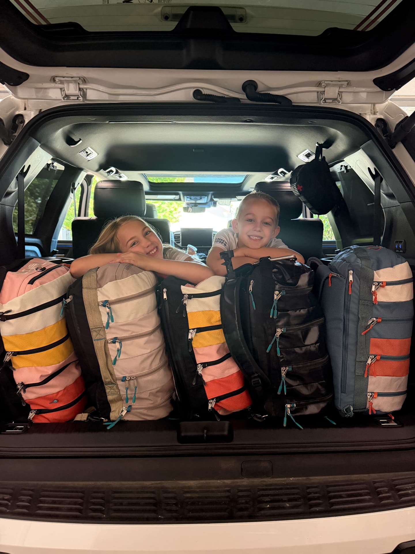 Aniston and Noah with our family's colorful 30L TOBIQ bags packed for Iceland
