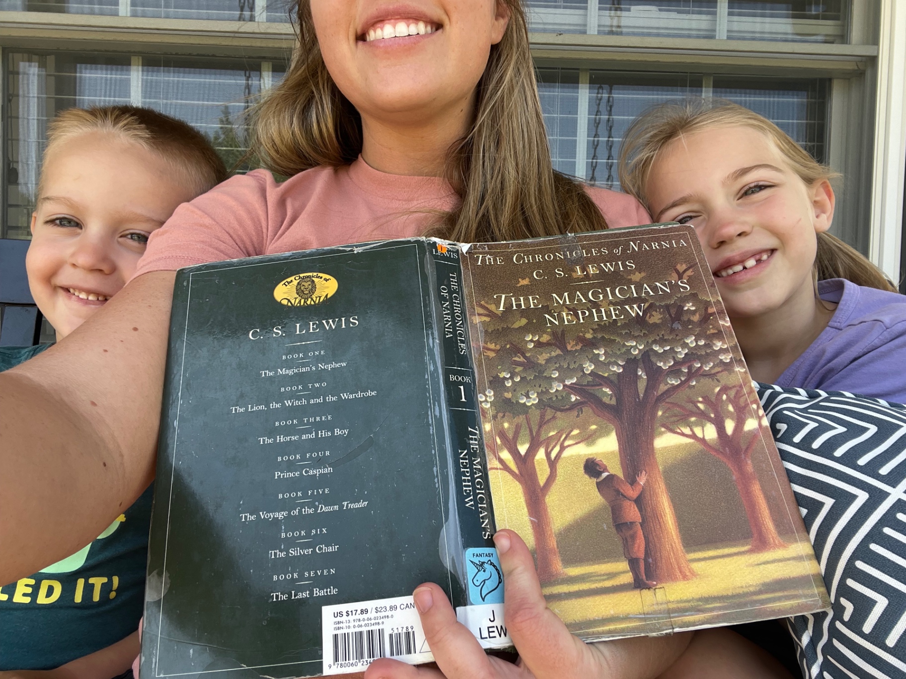 Brittany reading The Chronicles of Narnia on the porch with Aniston and Noah