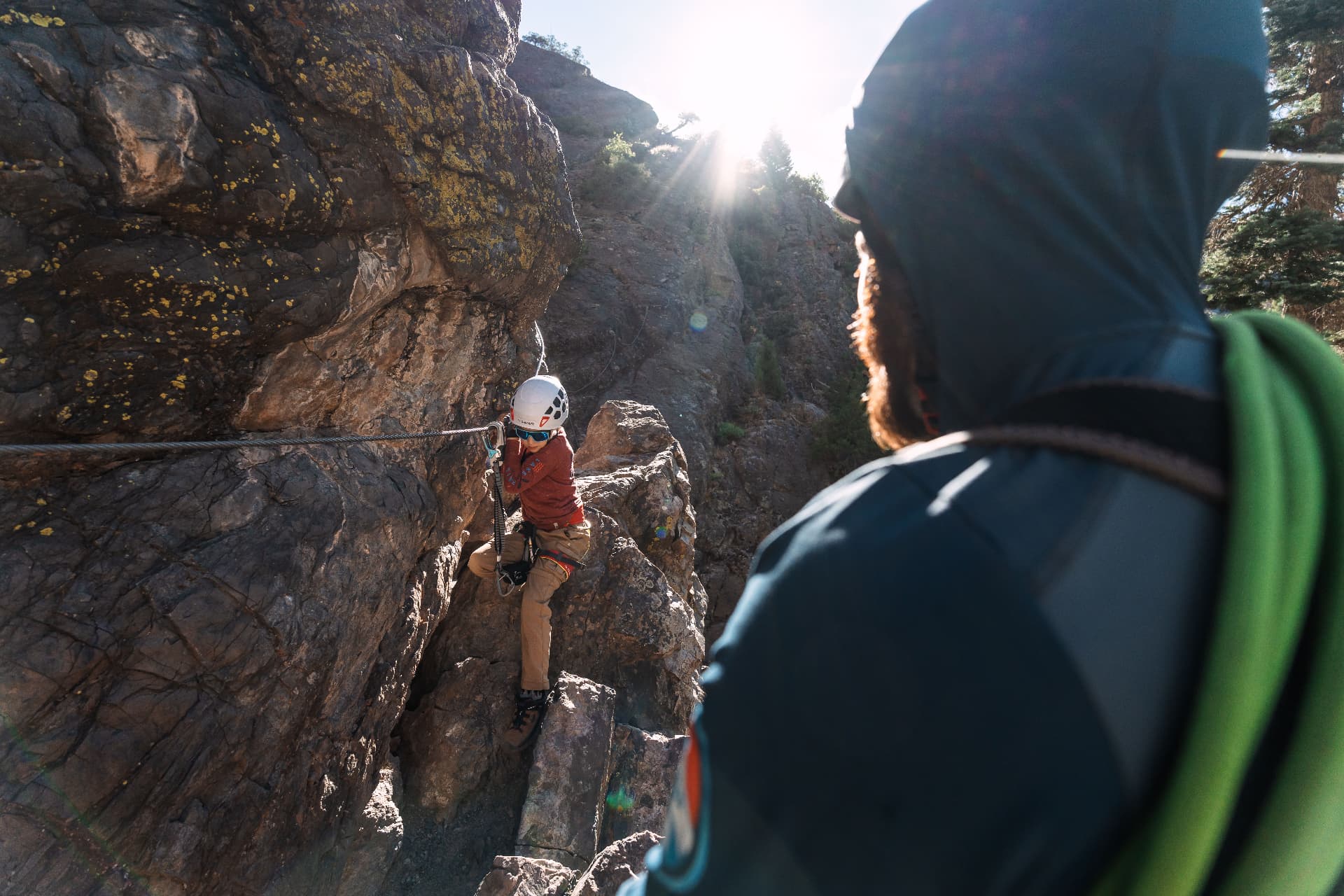 Our son climbing iron rungs along the cliff face as sunlight pours through the canyon