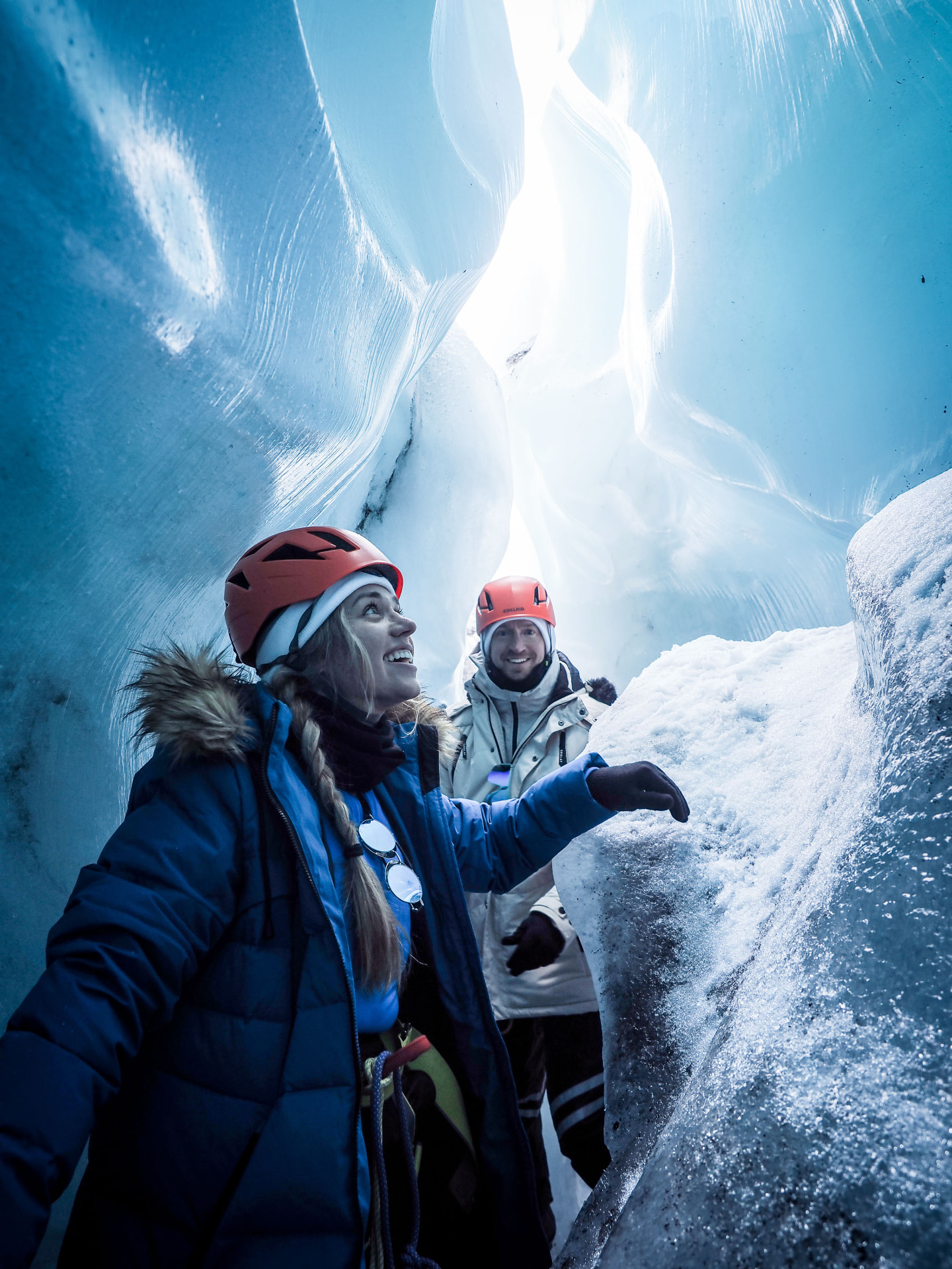 Brittany and Jake exploring a glowing blue ice cave in Iceland