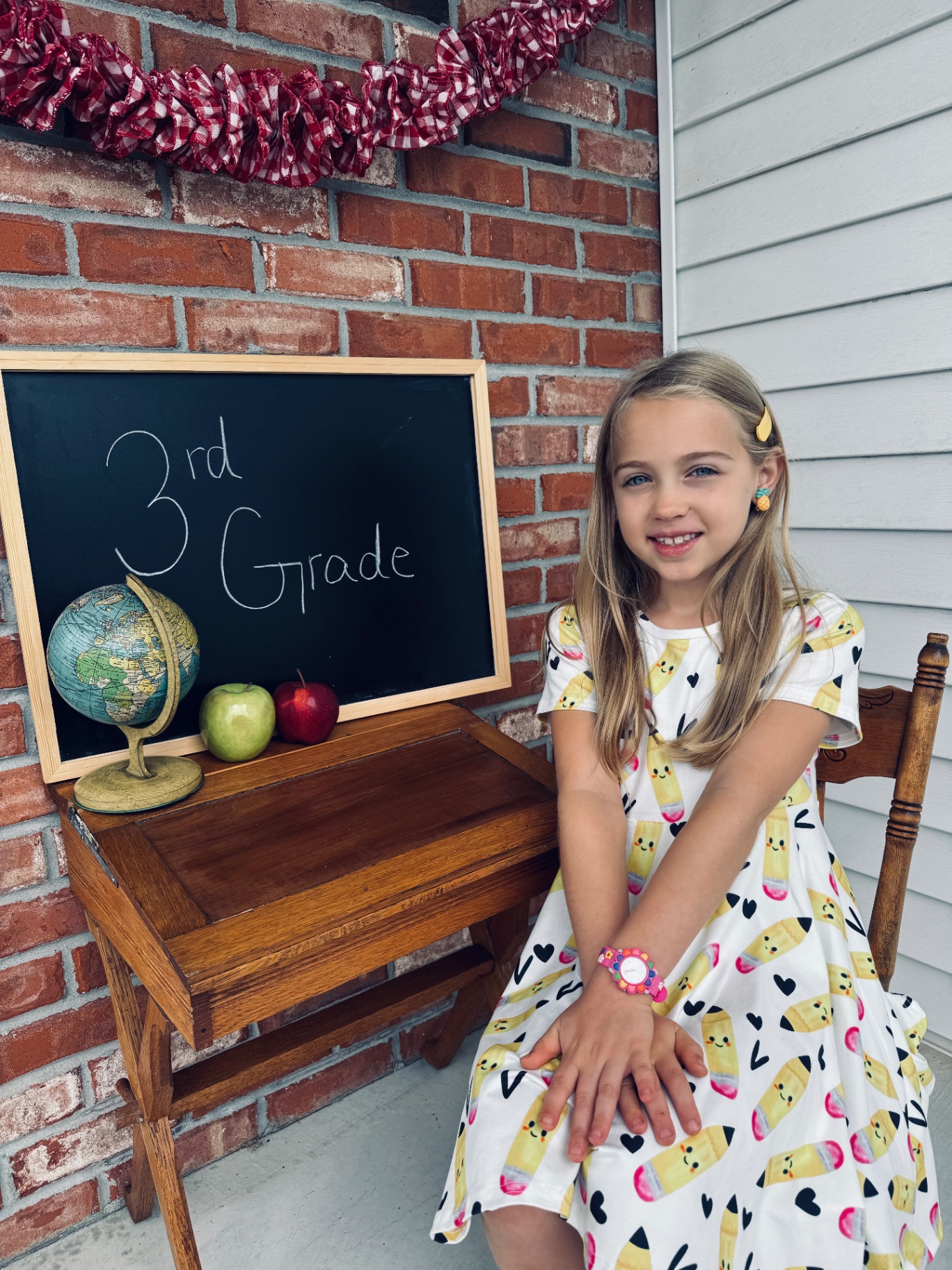 Aniston smiling next to a chalkboard that says 3rd Grade on the first day of homeschool