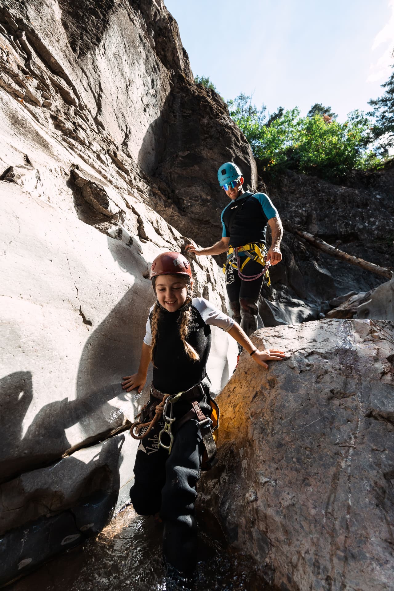 Our daughter down climbing between canyon walls with Jake spotting from above