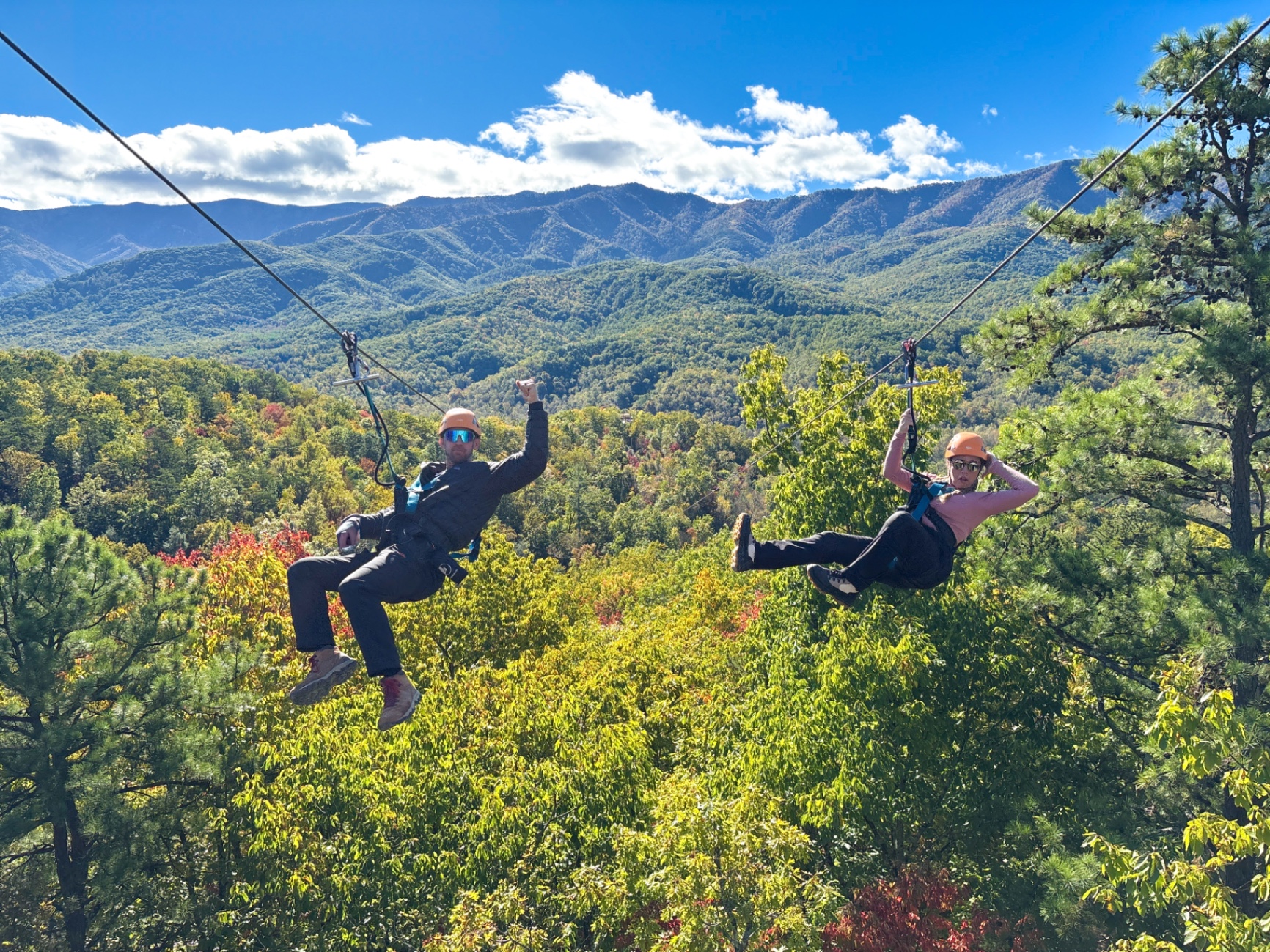Jake and Brittany ziplining side-by-side over the fall colors of the Great Smoky Mountains with CLIMB Works