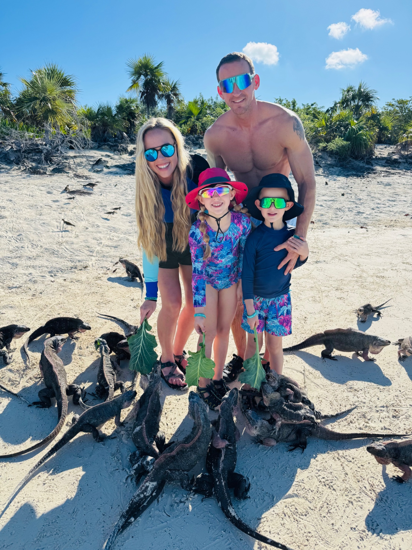 Jake, Brittany and their kids feeding iguanas on a Bahamas beach